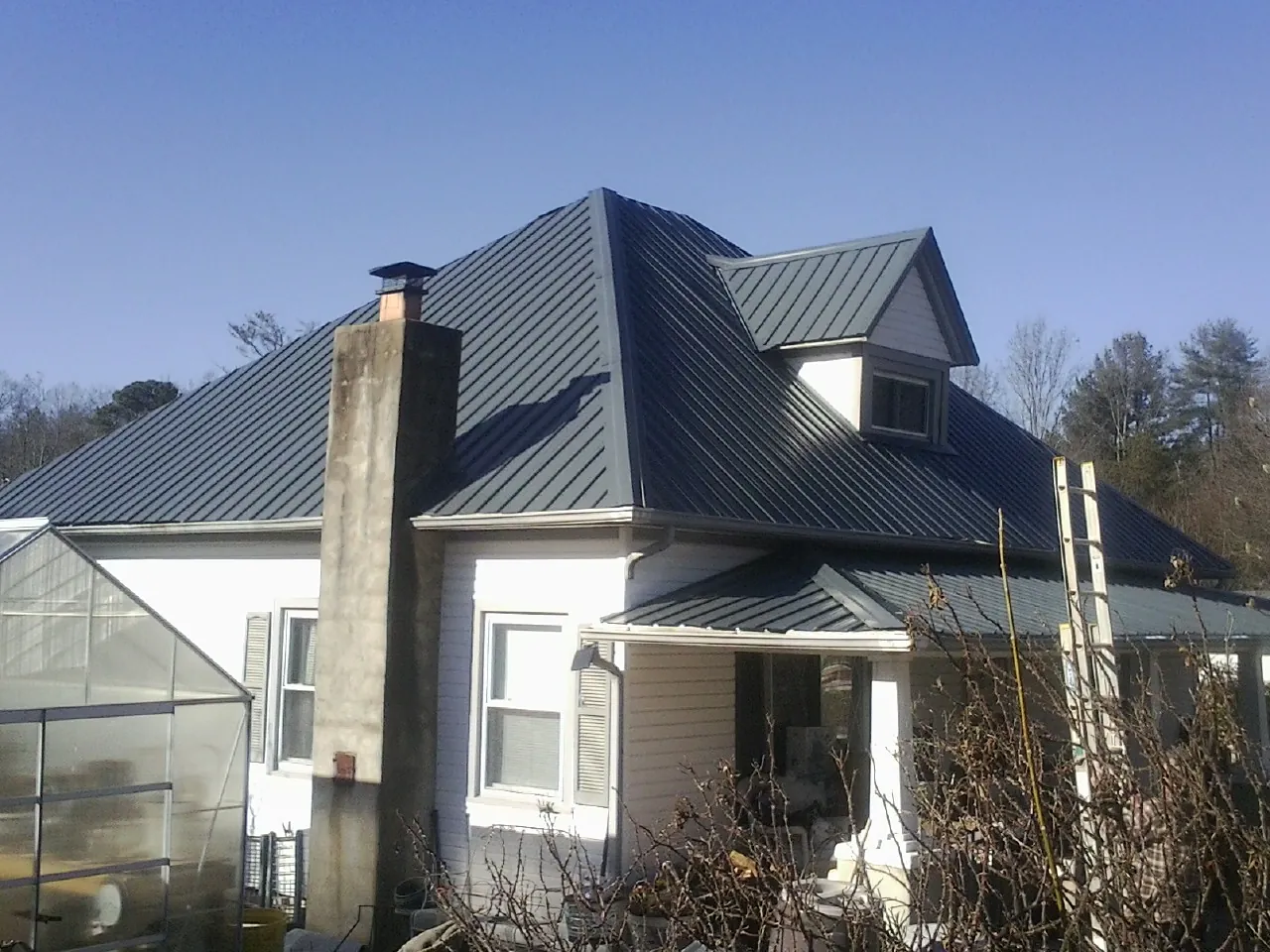 Dark blue standing seam metal roof on a white farmhouse with dormer — Slate & Tile Roof Repair by Roofing Brothers in Catasauqua