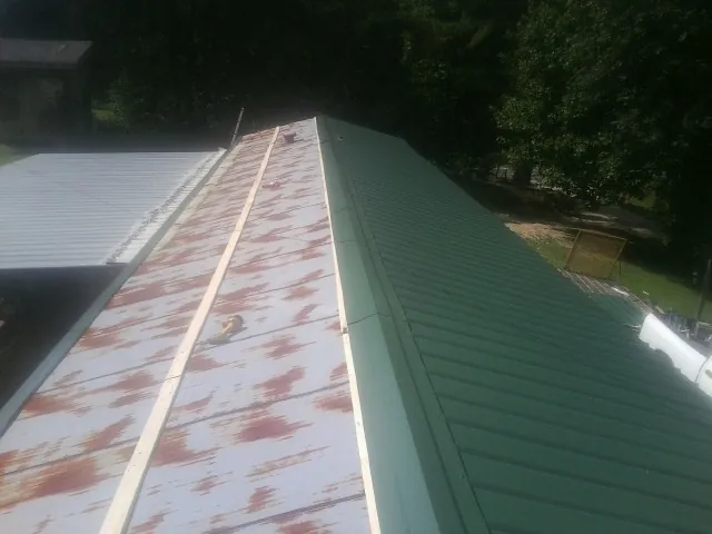 Old rusted panels beside newly installed green metal roofing — Wind Damage Roof Repair by Roofing Brothers in Catasauqua