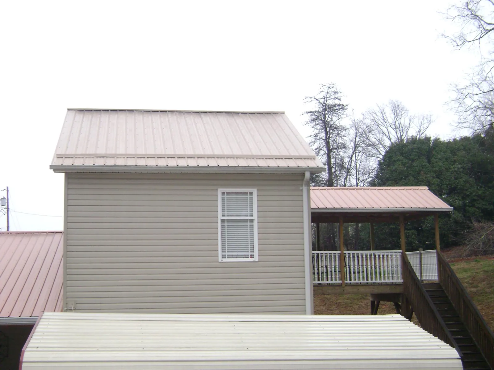 Tan metal roofs on a two story addition and attached porch, from a Roof Replacement job in Catasauqua