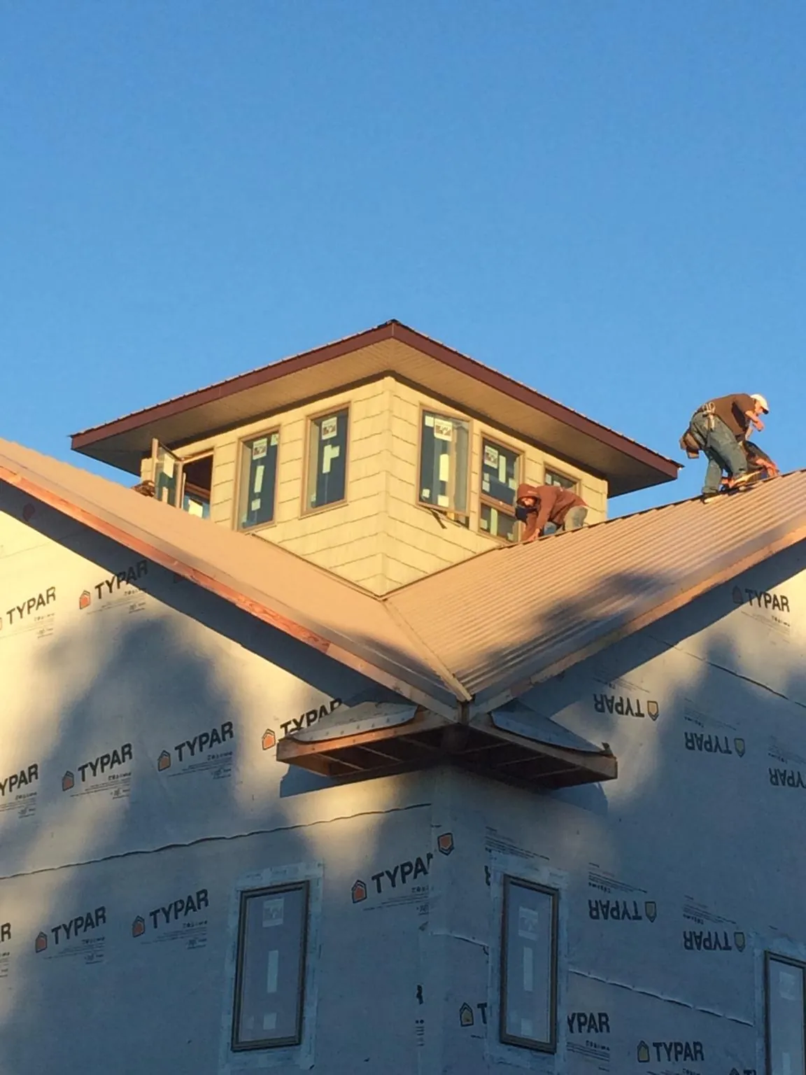 Roofers working around a rooftop cupola on a new metal roof at sunset — Roof Waterproofing in Catasauqua by Roofing Brothers